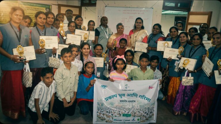 Village women and children holding certificates beside a TREEI banner