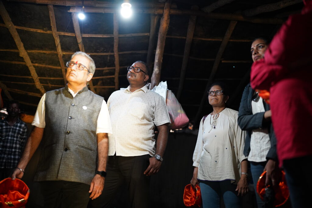 People standing indoors at night under electric lights, looking upward