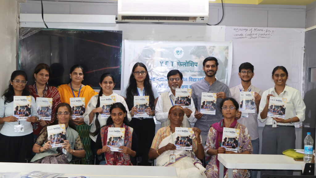 A group of people holding Y.E.T. fellowship booklets in an air-conditioned room with a banner in the background