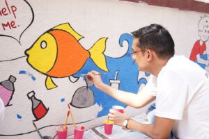 Energy Exemplar employee volunteer painting a school mural with TREEI