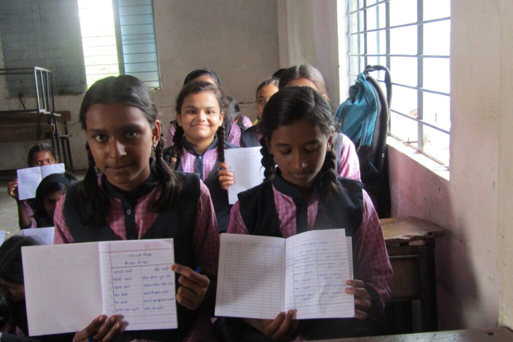 Two students show their life-skills workbooks