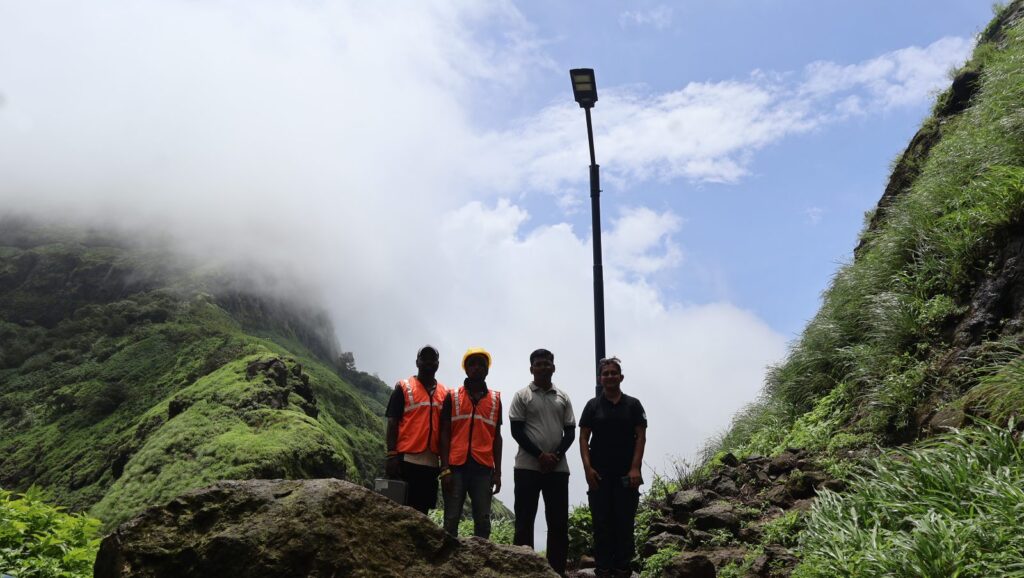 Mission URJA Fort Edition team beside a solar street light on a Sahyadri fort near Pune