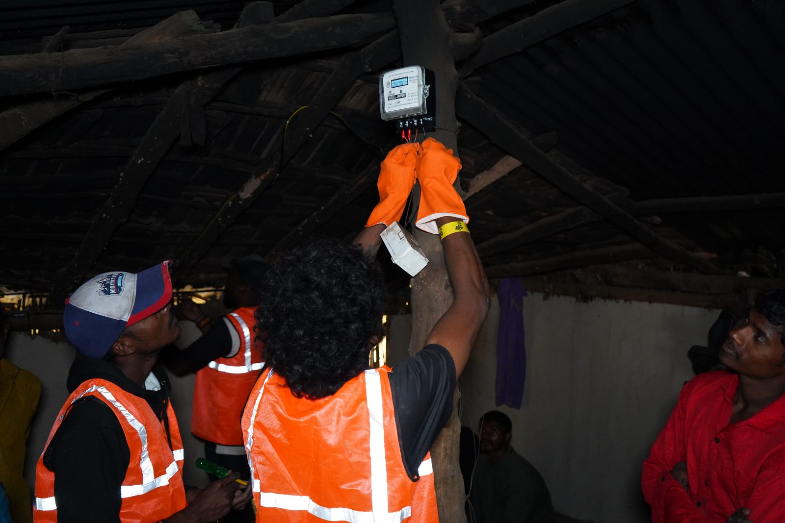 Mission URJA technicians wiring solar lights in a tribal hut after dark